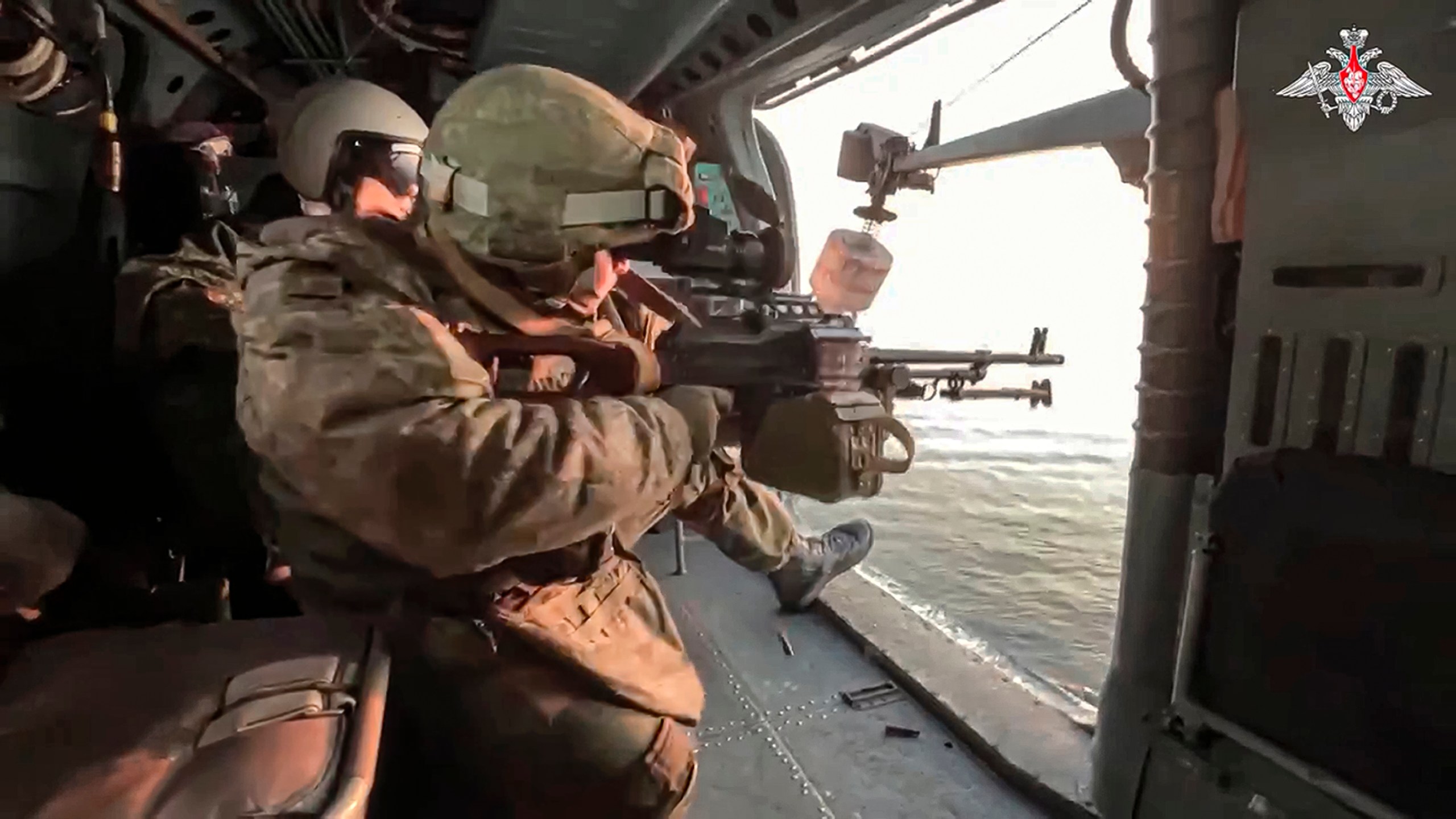 In this photo taken from video released by Russian Defense Ministry Press Service on Friday, Jan. 5, 2024, Russian soldiers fire from aboard a Ka-27 helicopter of the Russian Black Sea Fleet during a patrol the Black Sea. (Russian Defense Ministry Press Service via AP)